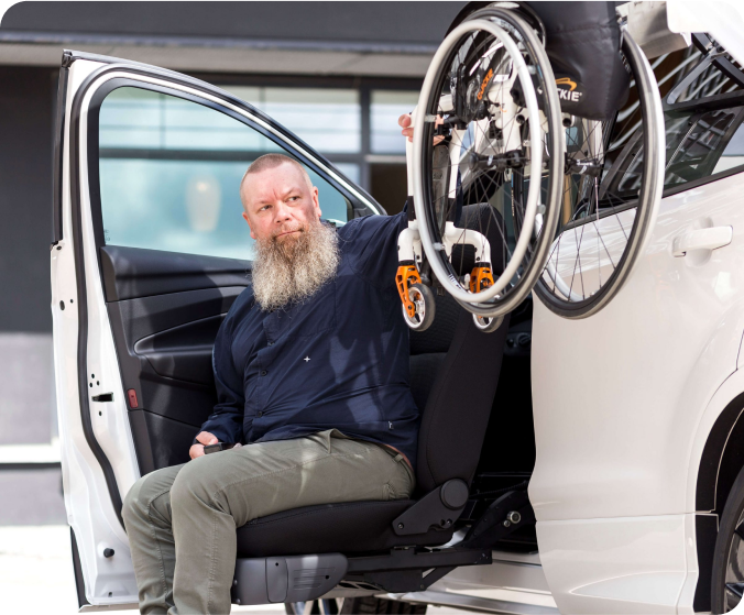 Personne utilisant un siège pivotant pour accéder à un véhicule équipé d’un système de chargement pour fauteuil roulant.