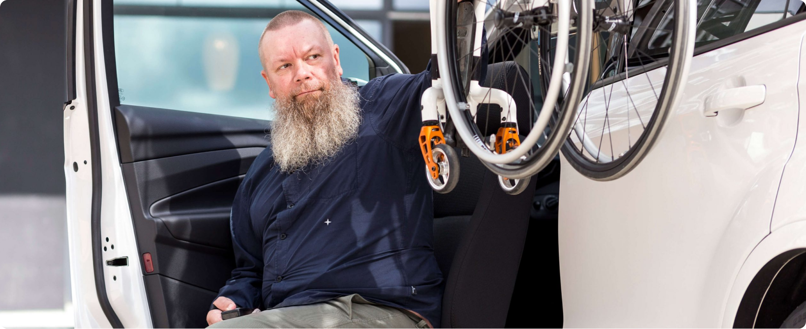 Personne utilisant un siège pivotant pour accéder à un véhicule équipé d’un système de chargement pour fauteuil roulant.