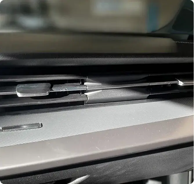 Sorties d’aération circulaires sur la console d’un véhicule, illustrant le système de ventilation et de climatisation.