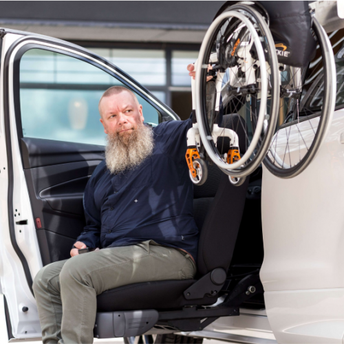 Personne utilisant un siège pivotant pour accéder à un véhicule équipé d’un système de chargement pour fauteuil roulant.