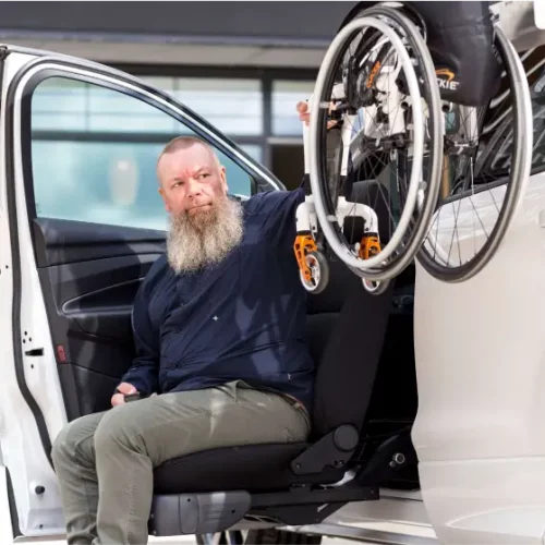 Personne utilisant un siège pivotant pour accéder à un véhicule équipé d’un système de chargement pour fauteuil roulant.